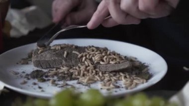 Eski etin huzurunu larvalarla kesen adamın elleri yakın çekimde. Çirkin, yemekler. Yemekte sapkın tatlar