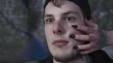 Başka bir yere bakan korkmuş bir adamın yakın çekim yüzü. Yüzüne dokunan siyah keskin tırnakları olan kadın eli. Kötü cadı erkek kurbanını yakaladı. Sihir, kötülük, büyüler