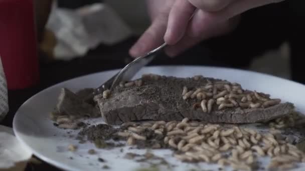 Człowiek z niecierpliwością tnie gotowane mięso nożem, na którym obrzydliwe robaki czołgają się w błocie. Zbliżenie. — Wideo stockowe