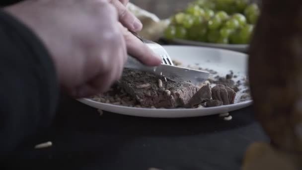 Самець з нетерпінням розрізає приготоване м'ясо за допомогою ножа, на якому огидно личинки просканують в багнюці. Закри. — стокове відео