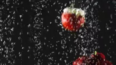 Düşen taze çilek ve kiraz siyah arka plan üzerinde köpüklü suya sıçrayan. Close.