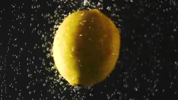 Limone fresco che cade in acqua su fondo nero. Agrumi in acqua con bollicine. Cibo biologico, stile di vita sano, dieta. Video con acceleratori . — Video Stock