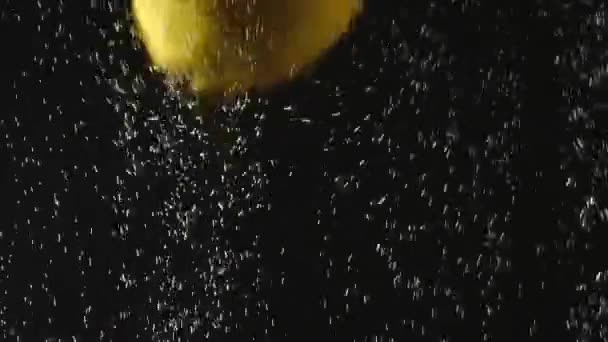Verse citroen die in het water valt met bubbels op zwarte achtergrond. Verse bessen in het water. Biologische bessen, fruit, gezonde voeding. Slow Motion. Video met accelerators. — Stockvideo