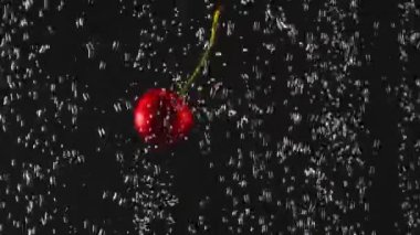 Siyah arka plan üzerinde köpüklü suya sıçrayan taze kiraz düşen. Suda meyve. Organik gıda. Yavaş çekim. Close