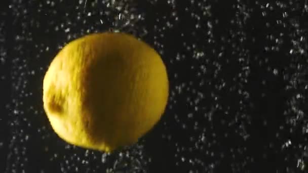 Čerstvé citrony padající do vody s bublinkami na černém pozadí. Čerstvé bobule ve vodě. Organická bobule, ovoce, zdravé jídlo. Zpomaleně. — Stock video