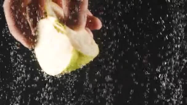 Mano masculina sosteniendo rebanada de manzana bajo el agua sobre fondo negro. Fruta fresca en el agua con burbujas. Comida orgánica, estilo de vida saludable, dieta. Concepto de verano — Vídeo de stock
