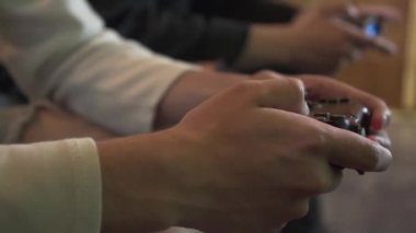 Yakın-up erkek elleri kanepede oturan oyun odasında video oyunu oynarken. Arkadaşlar joystick kullanarak mücadele. Video oyunu ve eğlence konsepti.
