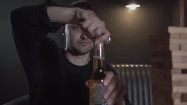 Genç adam odada ahşap kule oynarken bira şişesi açıyor. İçeride boş zaman. Oyun odasında dinlenen kaygısız adam. Konsept boş mekan