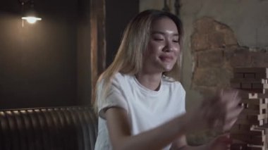 Portre sevimli genç kadın ahşap bloklar kule oynarken ve çatı tarzı odada bira içme. İçeride boş zaman. Oyun odasında dinlenen kaygısız kız. Konsept boş mekan