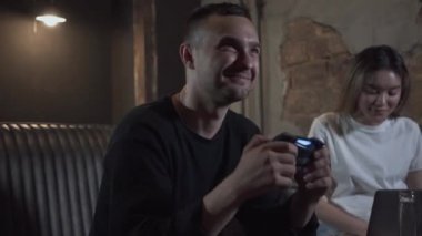 Loft tarzı odada video oyunu oynayan genç adam kız arkadaşı gülümseyerek kanepede oturuyor. Bir joystick kullanarak mücadele adam, kız ona destek yanında oturuyor. İç mekanlarda boş zaman