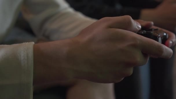 Manos masculinas jugando videojuegos en la sala de juegos sentadas en el sofá de cerca. Amigos peleando usando joysticks. Videojuego y concepto de ocio . — Vídeos de Stock