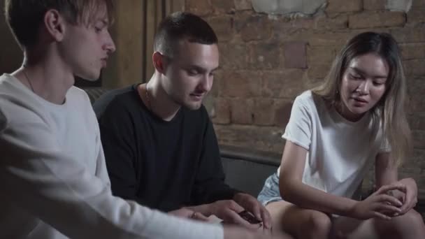 Beaux jeunes amis qui s'amusent le soir à jouer à des jeux de cartes avec une excellente humeur dans le loft club moderne. Concept loisir intérieur 