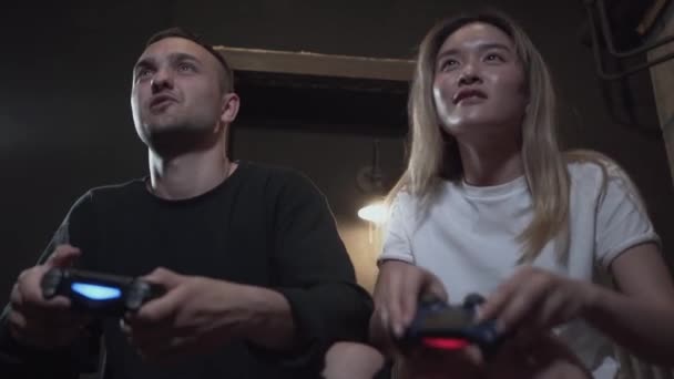 Portrait beau jeune homme avec sa fiancée s'amuser à jouer à des jeux vidéo avec une excellente humeur dans le club loft moderne. Jeu vidéo et concept de loisirs . — Video