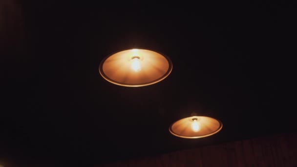 Empty bar in the gaming room in the loft style waiting for its visitors. Shelves with alcohol are highlighted. Old fashioned chandeliers with bulbs on the ceiling. Camera moving down — Stock Video