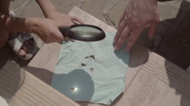 Küçük kızın elleri ve babasının loupe yakın çekim kullanarak peçete yakma. Çocuk bir ebeveynin gözetiminde dünyayı keşfeder. Yaz tatili