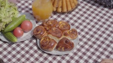 Taze pişmiş kek sebze ve meyve suyu kavanozu yakınında masada yatıyor. Anne, baba ve çocukların elleri aynı anda taze pasta parçaları alıyor. Mutlu dost aile kahvaltısı