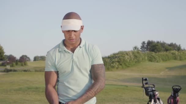 Portrétní, sebevědomý úspěšný muž středního východu s golfovým klubem, který stojí na golfovém hřišti za dobrého slunečného počasí. Sport a volný čas venku. Zpomaleně — Stock video
