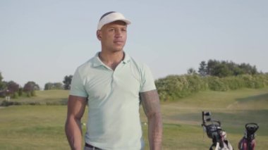 Yakışıklı emin başarılı orta doğu adam iyi güneşli havalarda bir golf sahası üzerinde duran bir golf kulübü ile. Spor ve eğlence açık havada. Yavaş çekim