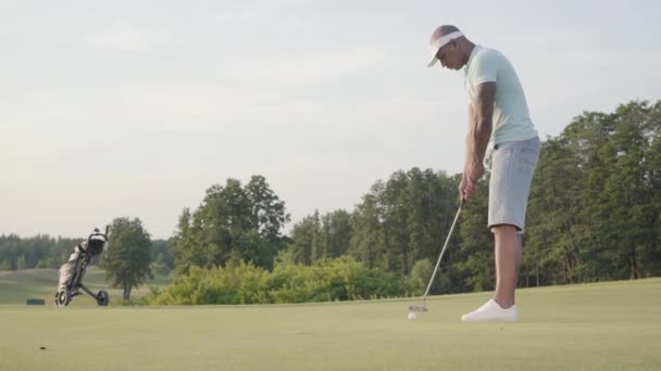 Un bell'uomo mediorientale che gioca a golf sul campo da golf. Tempo libero estivo — Video Stock
