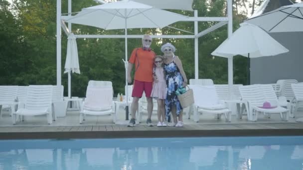 Šťastný dospělý pár stojí v bazénu a objímá svou malou vnučku. Babička a dědeček odpočívali s vnoučkem. Šťastná rodina. Odpočívej v hotelu — Stock video