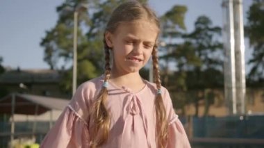 Açık havada tenis oynayan iki pigtails ile Portre sevimli komik kız. Konsantre çocuk bir raket ve topu geçmek üzere tutuyor. Yaz tatili