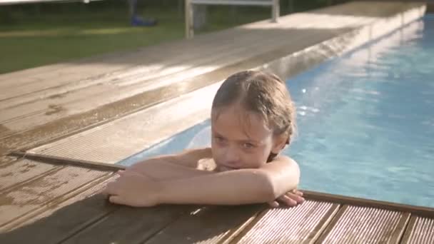 Adorable funny girl with pigtails laughing, showing thumb up looking out of the pool, holding on to the edge. Preteen child having fun in the hotel complex — Stock Video