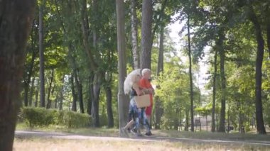 Mutlu olgun çift birlikte parkta yürüyüş. Elinde şemsiye tutan zarif kıdemli kadın. Yaşlı adam ve kadın dışarıda vakit geçiriyorlar, boş zamanlarıyla bağlantılılar. Yan görünüm