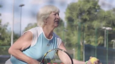 Tenis kortuna geçmek üzere olan raket ve top tutan olgun konsantre kadın. Açık havada aktif boş zaman. Tenis ağını arkadan çekim