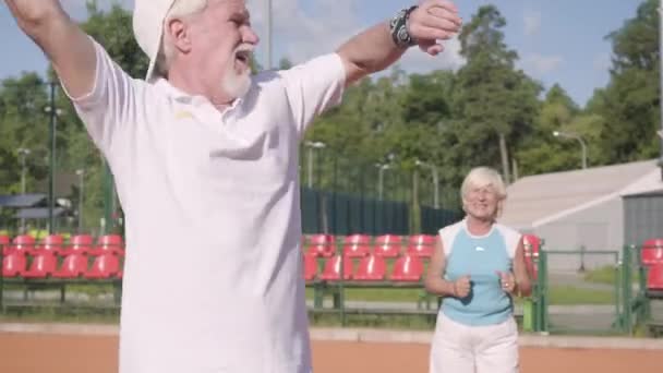 Porträtt upprörd äldre par förlorade turneringen på tennisbanan. Senior man och kvinna som håller huvudet med händerna håller racketar. Aktiv fritid utomhus. Begreppet nederlag — Stockvideo