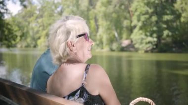 Mutlu sevimli olgun çift doğa hayran bankta oturuyor. Kıdemli erkek ve kadın birlikte dinleniyor. Açık havada boş zaman