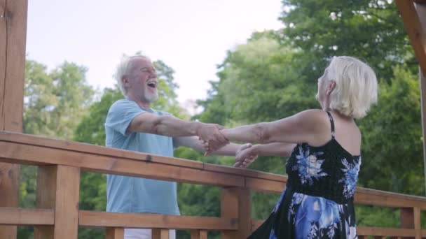 Pareja madura parada en el puente cogida de la mano hablando y sonriendo. Hermosa mujer mayor en vestido de verano y hombre barbudo en una cita. Relación romántica — Vídeos de Stock