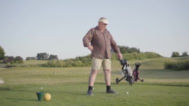Maçtan önce üst düzey bir adam ısınıyor, başının üstünde bir golf sopası tutuyor. Yaşlı beyefendi dışarıda oyun oynuyor. Yaz eğlence