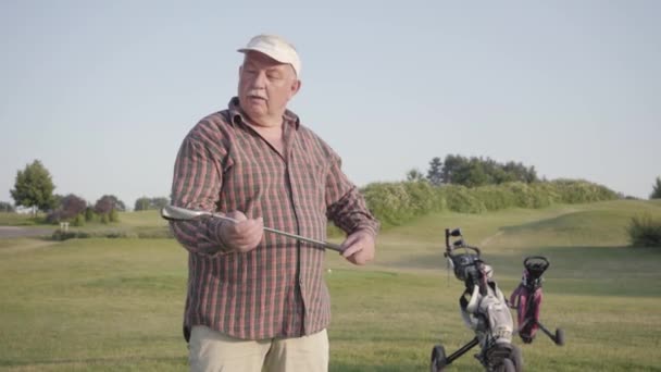 Porträtt säker framgångsrik mogen man stående med en Golf clubon en golfbana i gott soligt väder. Sport och fritid utomhus. — Stockvideo