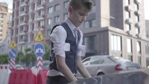 Le petit garçon remonte les manches et lève le capot de la voiture. Garçon confiant va réparer l'automobile lui-même. Enfant adulte — Video