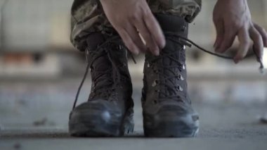 Eski ayakkabılarını bağlayarak eğitime hazırlanırken kadın ellerinin yakın çekim. Terk edilmiş bir fabrikada savaşçı kadın.