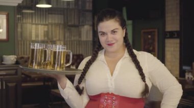 Beyaz bluz ile pigtails ile tombul kadın kamera gülümseyen üç bira gözlükleri ile tepsi tutuyor. Barda boş zaman. Reklam konsepti.
