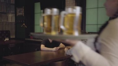 Beyaz bluz ve korse barda masada oturan erkeklere soğuk bira getiren pigtails ile tombul garson. Kafede boş zaman