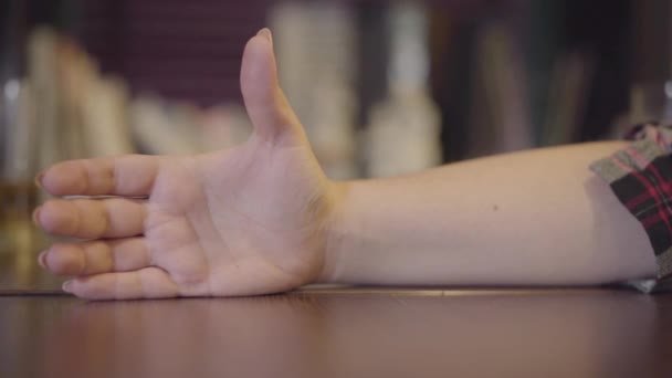 Ein Glas leichtes Bier rutscht langsam auf den Tisch und fällt in Großaufnahme in die Hand eines Mädchens. Freizeit an der Bar. Zeitlupe — Stockvideo