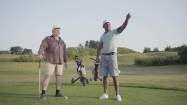 Olgun Kafkas adam ve Golf Sahası üzerinde Golf oynarken genç Orta Doğu adam. Erkekler tarafa doğru hareket ederler, bakar ve tartışır. Yaz eğlence.