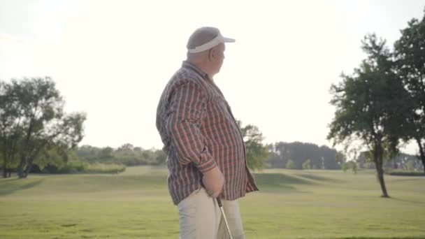 Portret udany dojrzały golfista golfa na pięknym kursie. Pewny siebie człowiek stojący w słonecznej letniej pogodzie stojący w słońcu na zewnątrz. Koncepcja rekreacji i sportu na zewnątrz. — Wideo stockowe