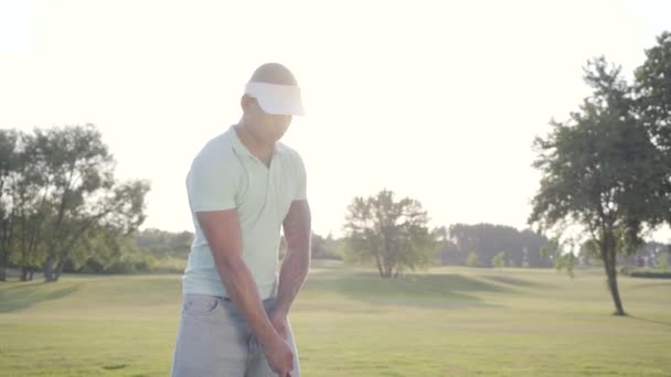 Portrait successful middle eastern golfer swinging and hitting golf ball on beautiful course. Confident man golfing in beautiful sunny summer weather standing in the sunshine. — Stock Video