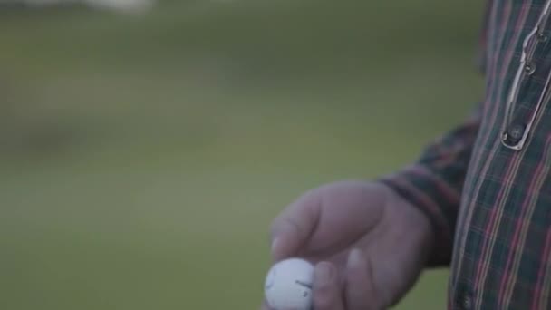 Close-up mão de homem maduro vomitando e pegar bola de golfe de pé no campo de golfe. Um velho cavalheiro a jogar ao ar livre. Lazer de verão — Vídeo de Stock