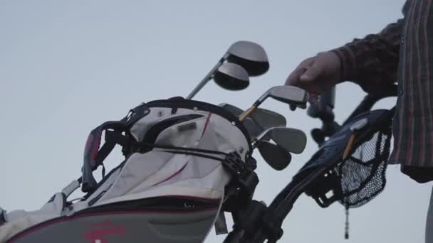 Una mano de hombre escoge un palo de golf de un club de pie de cerca. El tipo que juega al golf en el campo de golf. El concepto de recreación y deportes al aire libre. Vista inferior — Vídeos de Stock