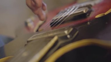 Beceri tanınmayan adam bir gitar yakın çekim dizeleri oynuyor.