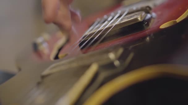 Hånden af en ukendt mand spiller strengene af en guitar close-up . – Stock-video