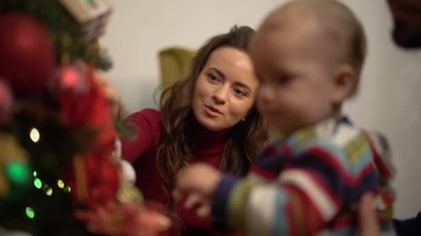 La familia decora el árbol de Navidad. La familia feliz celebra la Navidad juntos. Movimiento lento . — Vídeos de Stock