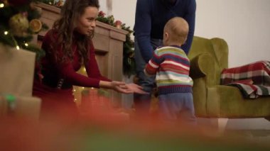 Şirin neşeli neşeli Anne, baba ve bebek evde Noel ağacının yanında boş zamanlarını harcamak.