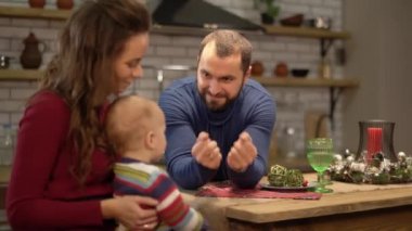 Anne, baba ve bebek modern mutfakta eğleniyoruz. Baba ve anne çocuk ile oynuyor, adam bir seçim için teklif gizlenmiştir şekerlemeler ile iki yumruklar gösterir. Mutlu aile birlikte zaman harcamak
