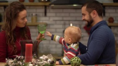 Modern mutfakta masada oturan anne, baba ve Bebek portresi. Babam onun turunda sevimli, ciddi bir çocuk çocuğu tutuyor. Mutlu aile birlikte zaman harcamak.