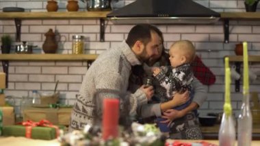 Sıcak kazak içinde sakallı baba mutfakta anne kollarda bebek küçük oğlu ile oynuyor. Adam çocuğa biber pot verir ve o sallar. Mutlu dost aile birlikte zaman harcamak